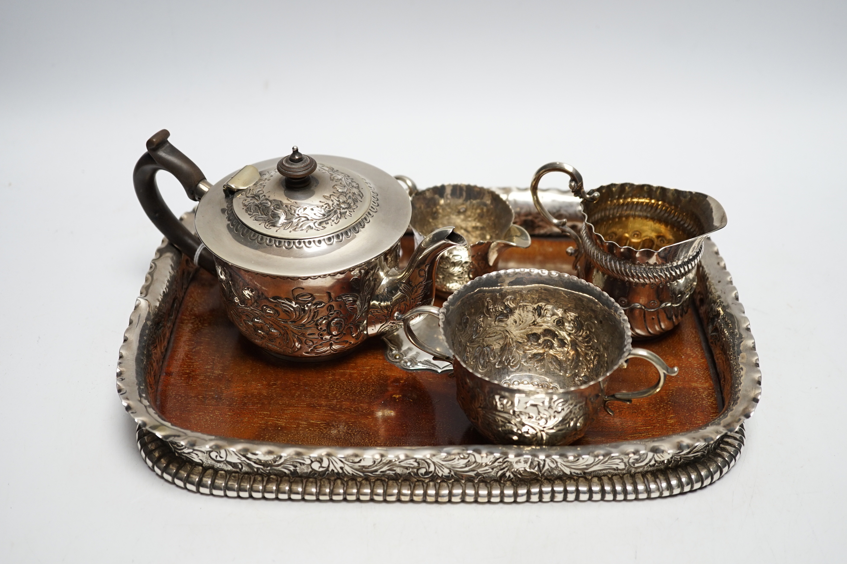 A matched Victorian repousse silver four piece bachelor's tea set, gross 12.8oz and silver plated? mounted wooden tea tray.